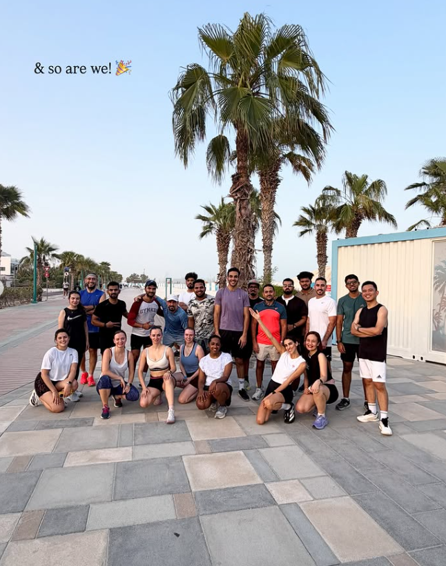 Croissant Run Club members gathered beneath palm trees in Dubai
